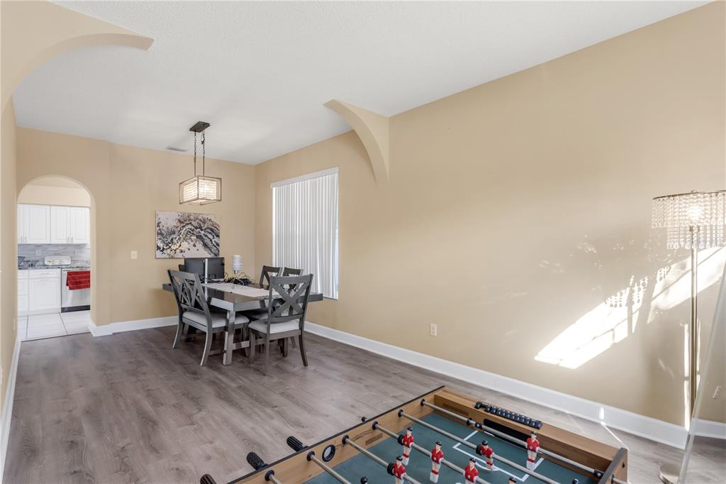 A dining area with wood-look flooring, a foosball table, and an arched entryway to the kitchen — 11436 GEORGETOWN CIRCLE, TAMPA, FL