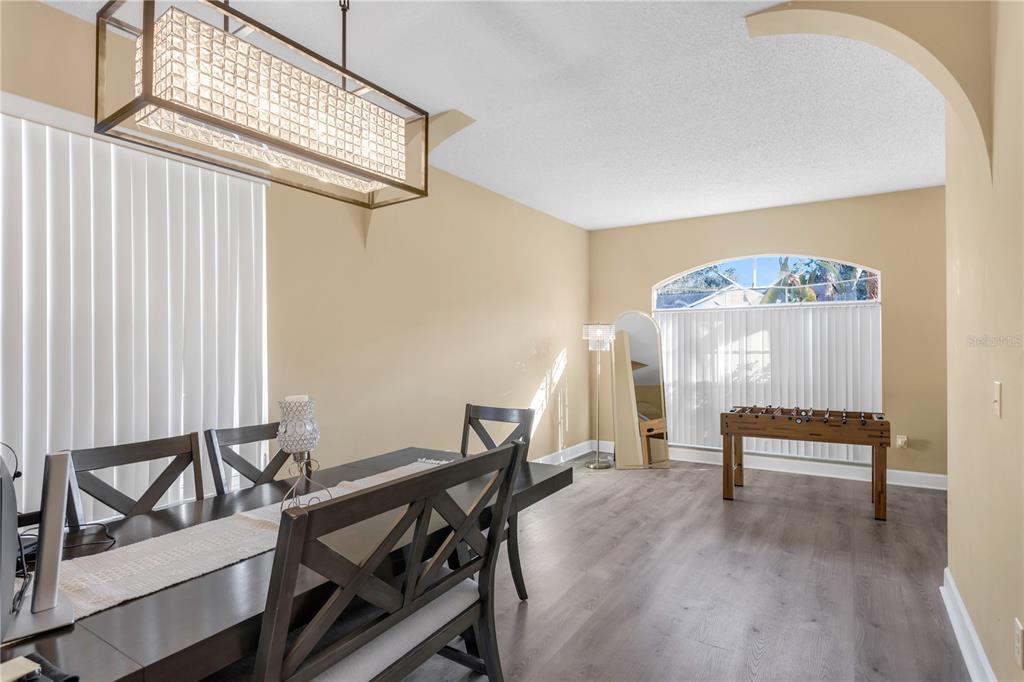 A dining room features a rectangular chandelier, dark wood furniture, and a foosball table — 11436 GEORGETOWN CIRCLE, TAMPA, FL