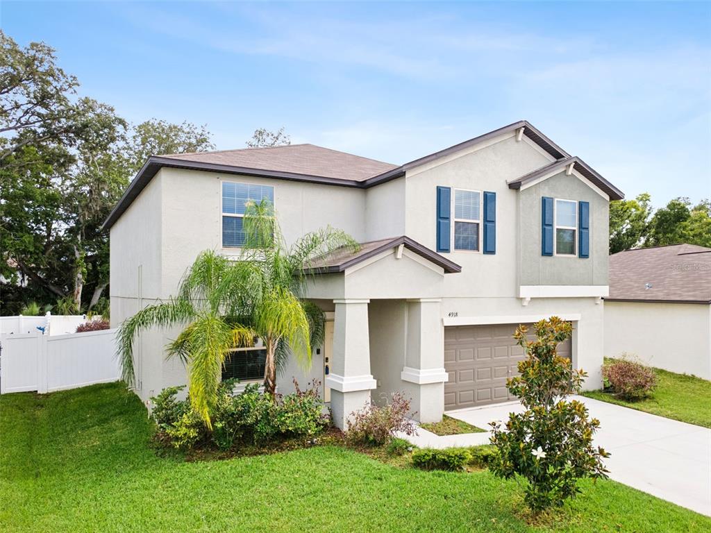 A two-story suburban house features a beige stucco exterior, blue shutters, and a two-car garage — 4918 WILD SENNA BOULEVARD, TAMPA, FL