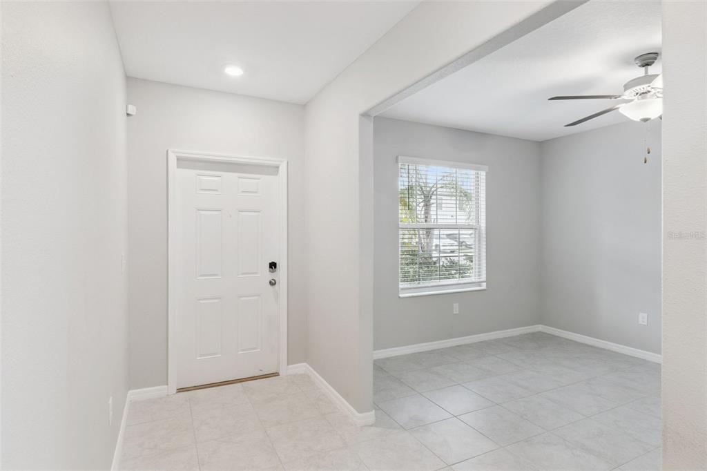 An entryway with a white door leads into a tiled room featuring a ceiling fan — 4918 WILD SENNA BOULEVARD, TAMPA, FL
