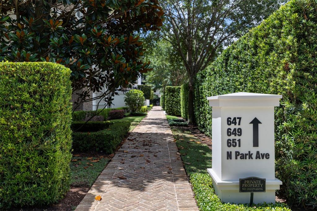 A brick walkway leads through a landscaped garden toward a sign indicating building numbers — 649 N PARK AVENUE, WINTER PARK, FL