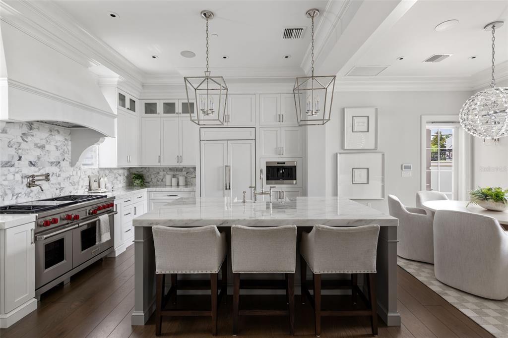 A white kitchen features a marble-topped island, stainless steel appliances, and dark wood flooring — 649 N PARK AVENUE, WINTER PARK, FL