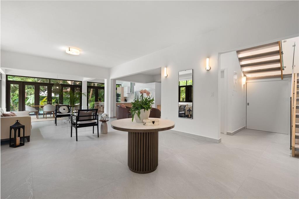 A bright, open-concept foyer features a round pedestal table, tiled floors, and a floating staircase — The Legends DORADO BEACH EAST UNIT 25, DORADO, PR
