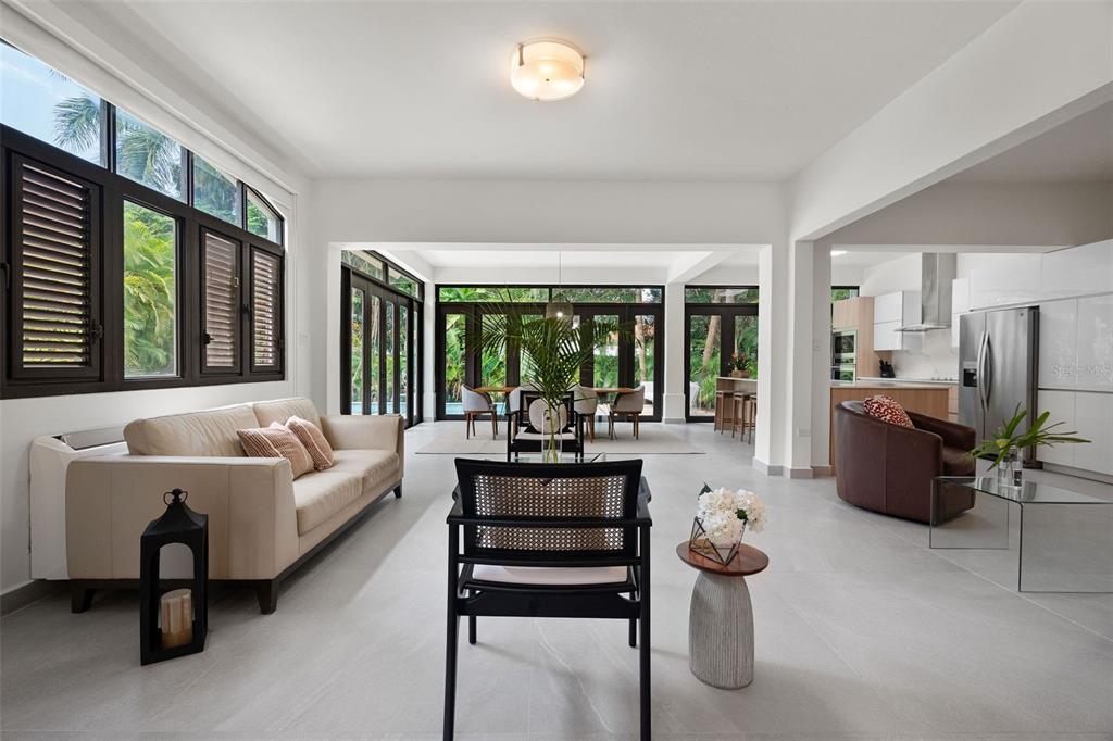 A bright, open-concept living and dining area features white tile floors and dark window frames — The Legends DORADO BEACH EAST UNIT 25, DORADO, PR