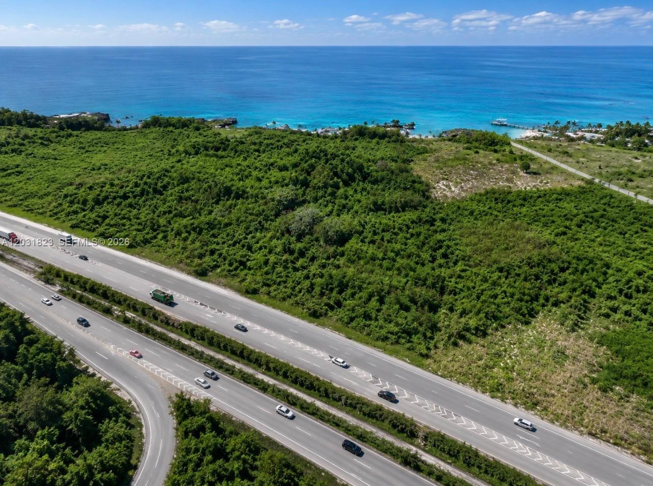 An aerial view shows a coastal highway bordering a large, undeveloped wooded lot near the ocean — Autovia Del Este, PA 15400, PA