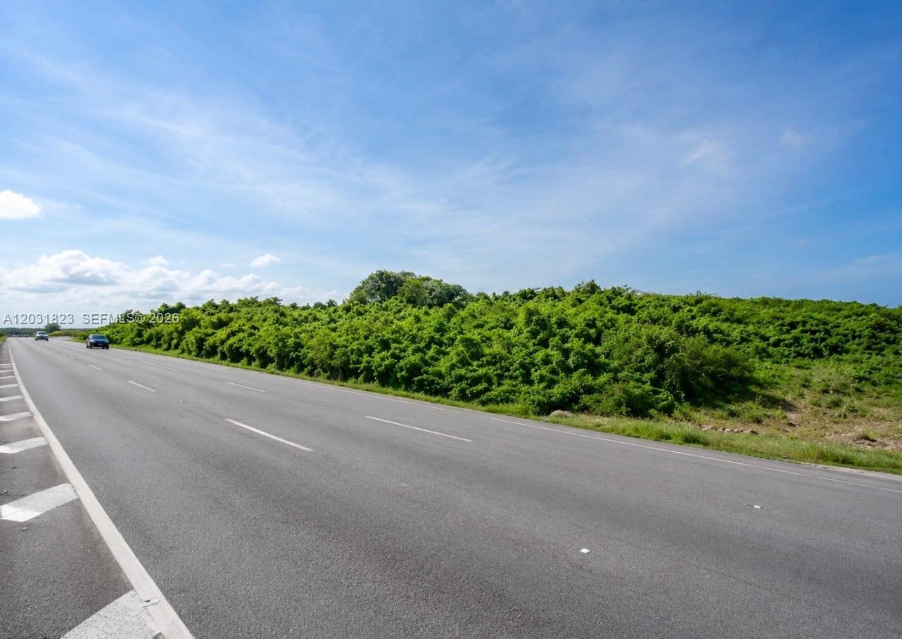 An aerial view shows a highway running alongside a dense forest bordering the ocean — Autovia Del Este, PA 15400, PA