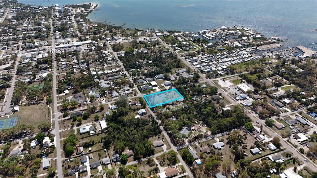 An aerial view shows a residential neighborhood with a vacant lot highlighted in blue — 212 CEDAR STREET, ENGLEWOOD, FL
