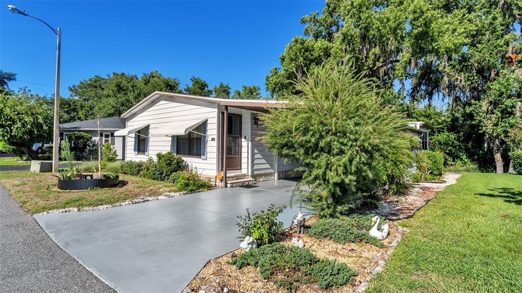 A single-story white house with a gray driveway and a covered front entryway — 4959 COLONNADES CIRCLE W, LAKELAND, FL
