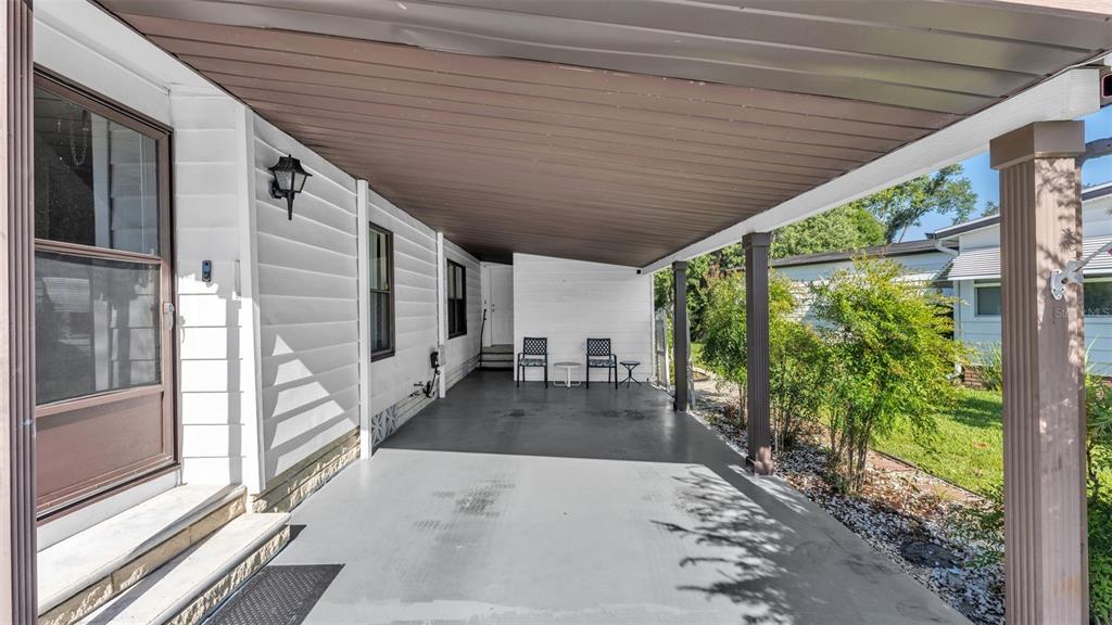 A covered carport with a concrete floor, support columns, and a side entrance to the home — 4959 COLONNADES CIRCLE W, LAKELAND, FL