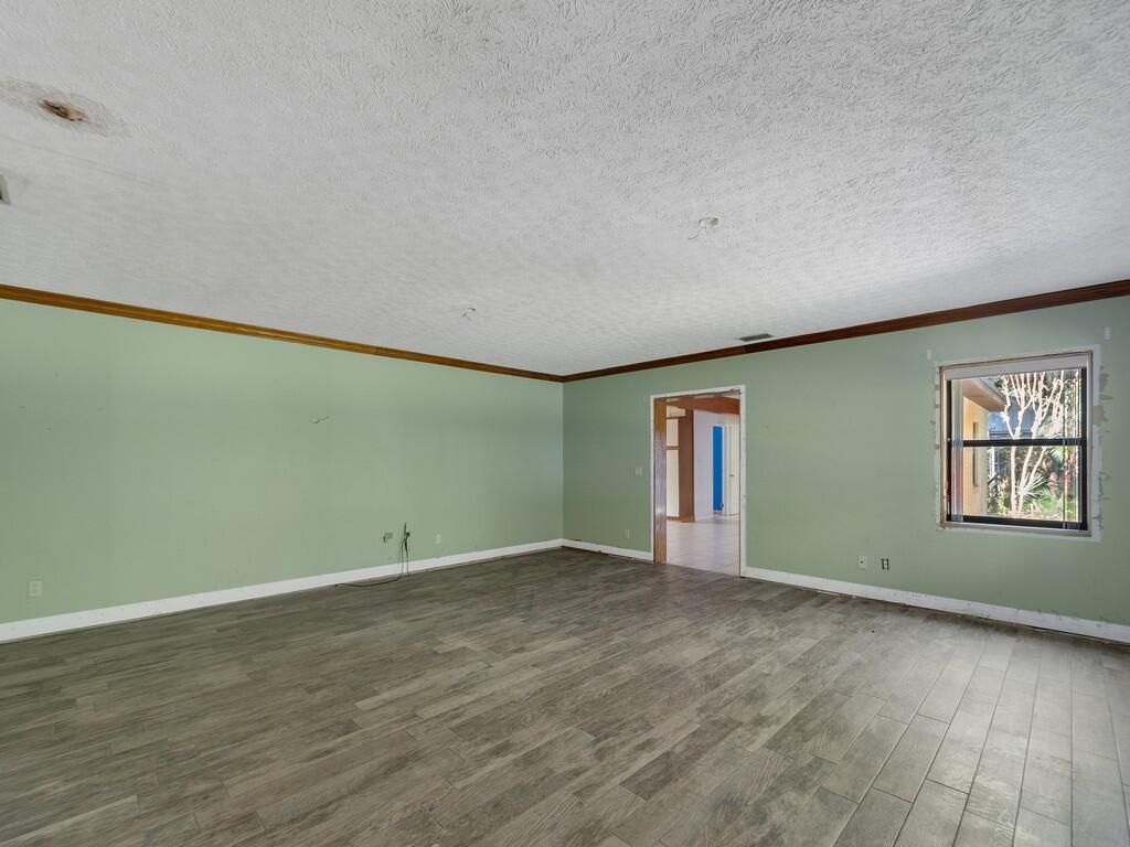 An empty room with sage green walls, wood-look tile flooring, and a single window — 1408 Russell Lane, Fort Pierce FL 34982, FORT PIERCE, FL