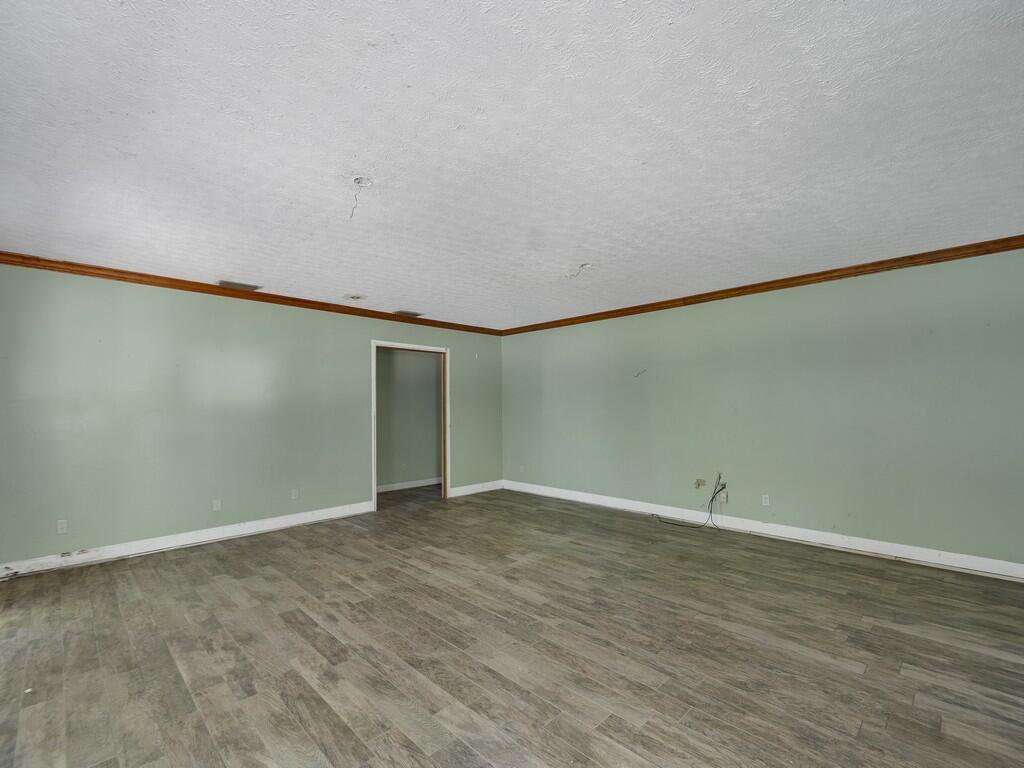 An empty room features light green walls, wood-look flooring, and a white ceiling with molding — 1408 Russell Lane, Fort Pierce FL 34982, FORT PIERCE, FL