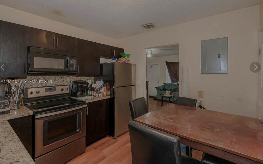 A kitchen features dark wood cabinets, stainless steel appliances, granite countertops, and a dining table — 110 NW 32nd Ave, Lauderhill FL 33311, LAUDERHILL, FL