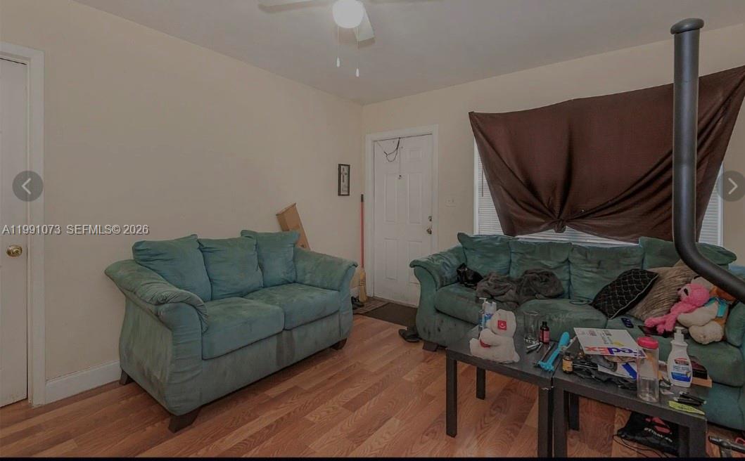 A living room features two teal sofas, wood-look flooring, and a ceiling fan — 110 NW 32nd Ave, Lauderhill FL 33311, LAUDERHILL, FL