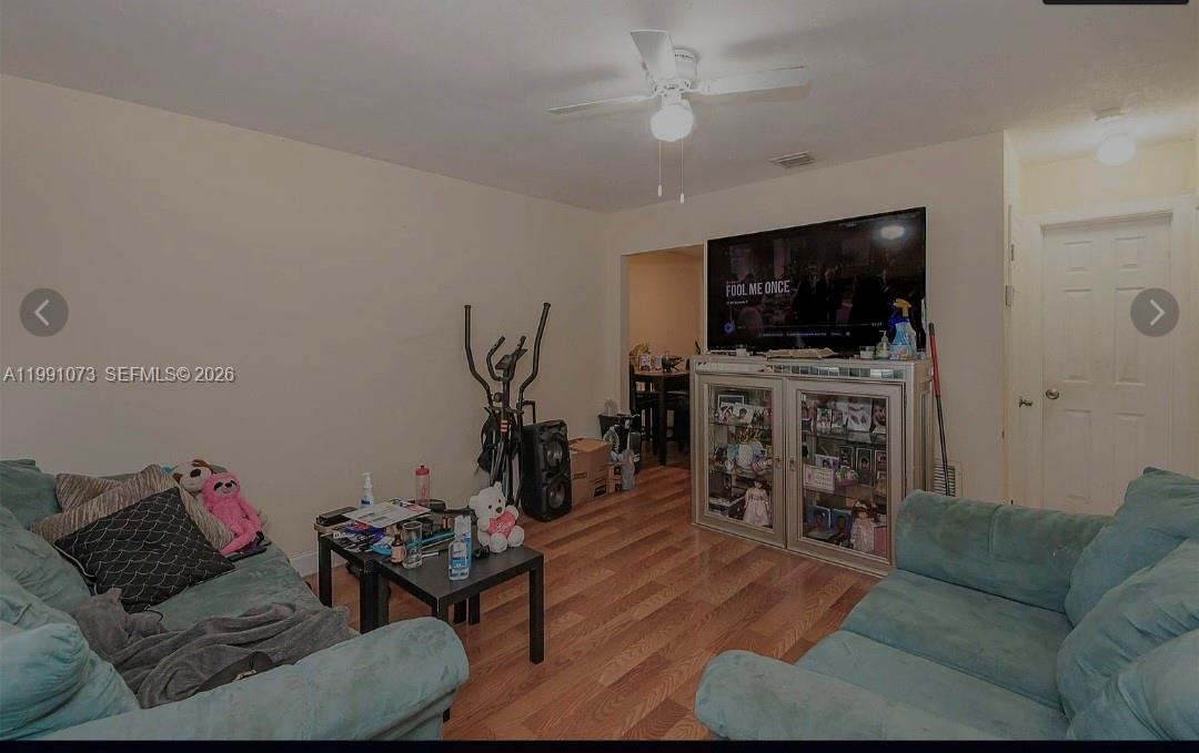 A living room features light-colored walls, wood-look flooring, two teal sofas, and a ceiling fan — 110 NW 32nd Ave, Lauderhill FL 33311, LAUDERHILL, FL