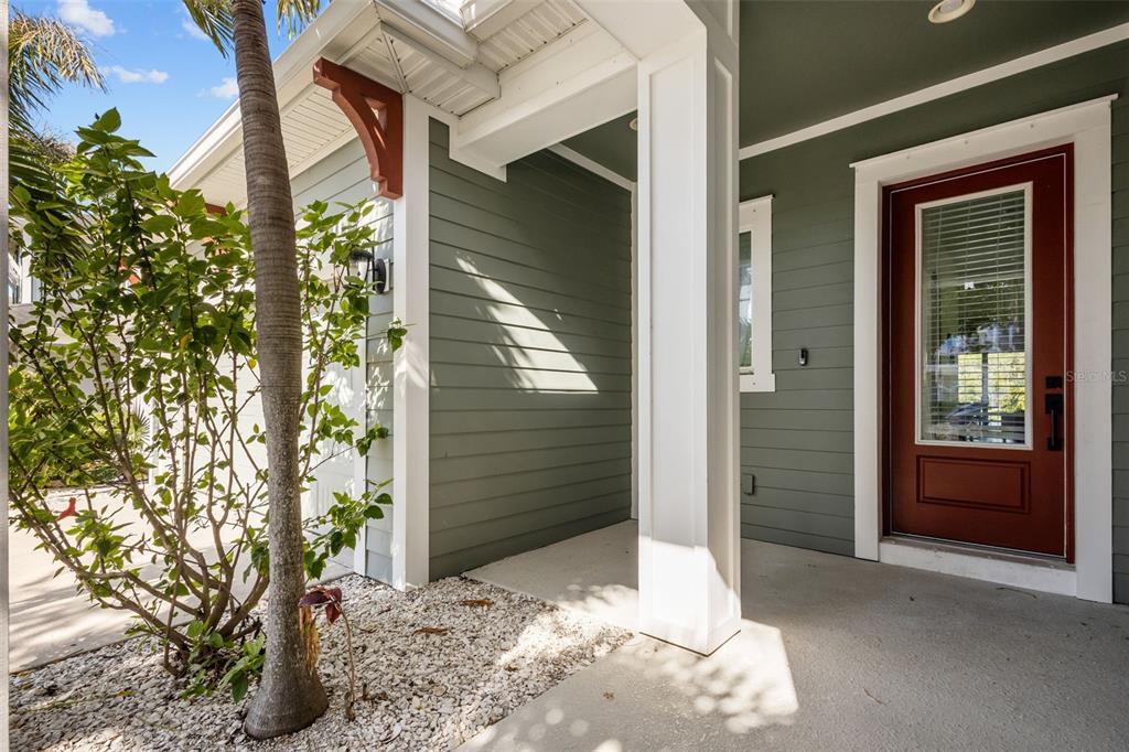 A covered front porch features green horizontal siding, a red door, and a white pillar — 2515 PORTICO STREET, ODESSA, FL