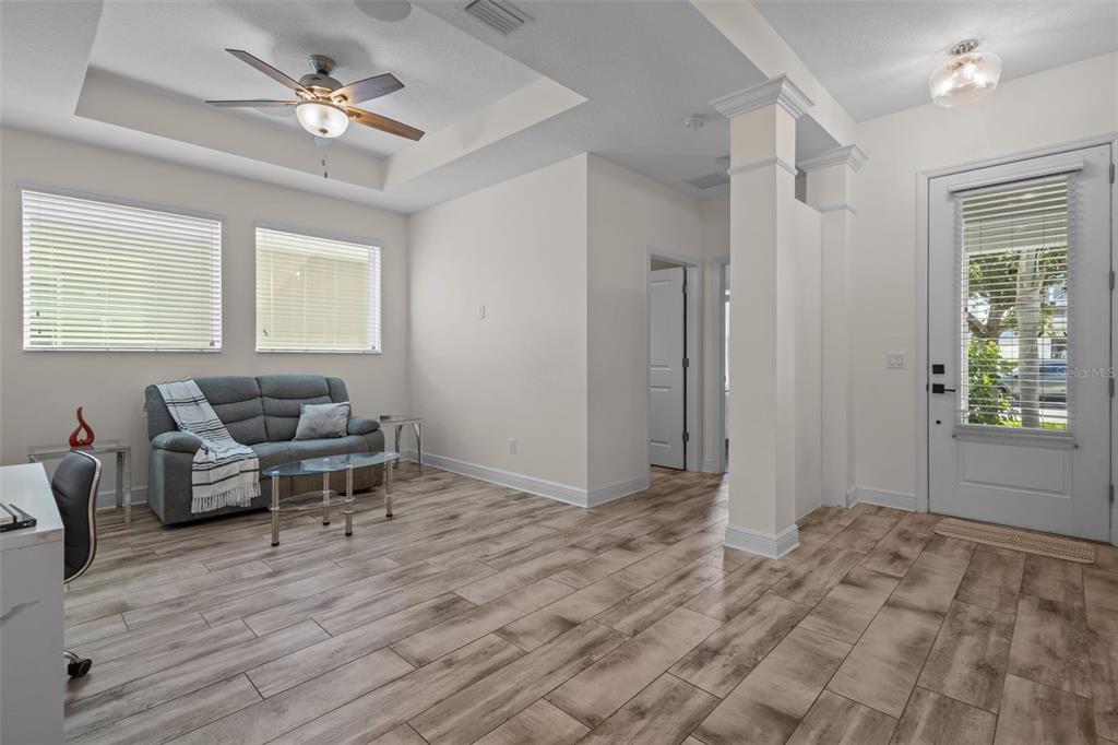 A living room features wood-look tile flooring, a tray ceiling with a fan, and a sofa — 2515 PORTICO STREET, ODESSA, FL