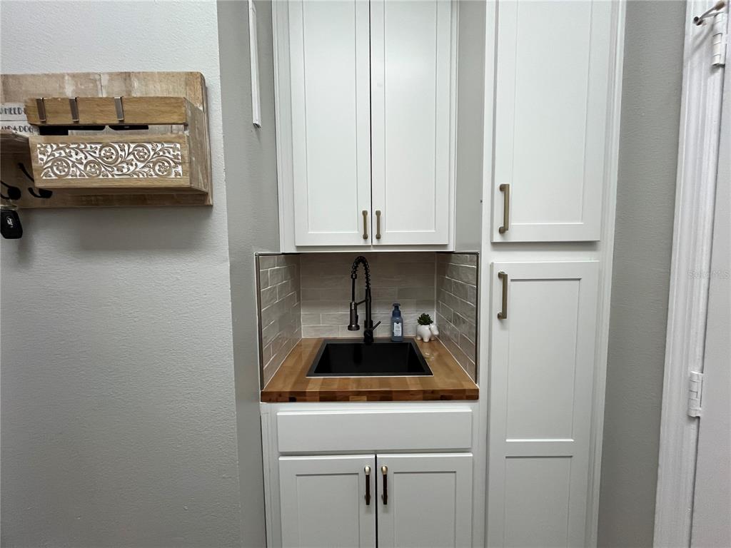 A small wet bar features white cabinets, a butcher block countertop, and a black sink — 10839 LANTANA CREST, CLERMONT, FL