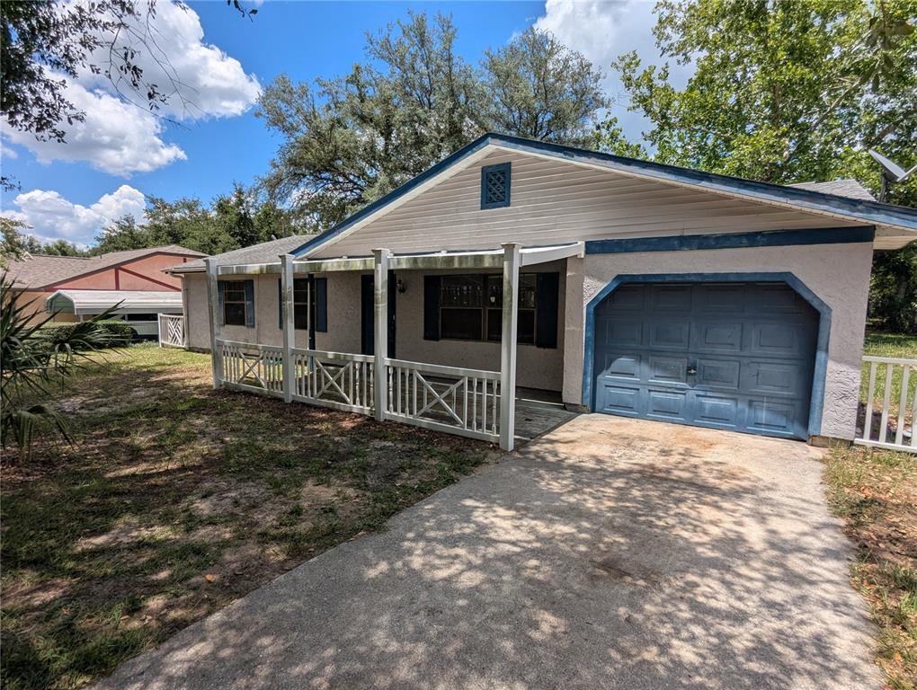 A single-story house with a blue garage door, front porch, and light-colored stucco exterior — 32 PALM RUN, OCALA, FL