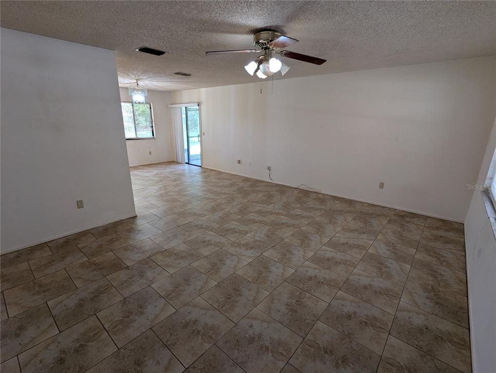 An open-concept living area features light-colored tile flooring, white walls, and a ceiling fan — 32 PALM RUN, OCALA, FL