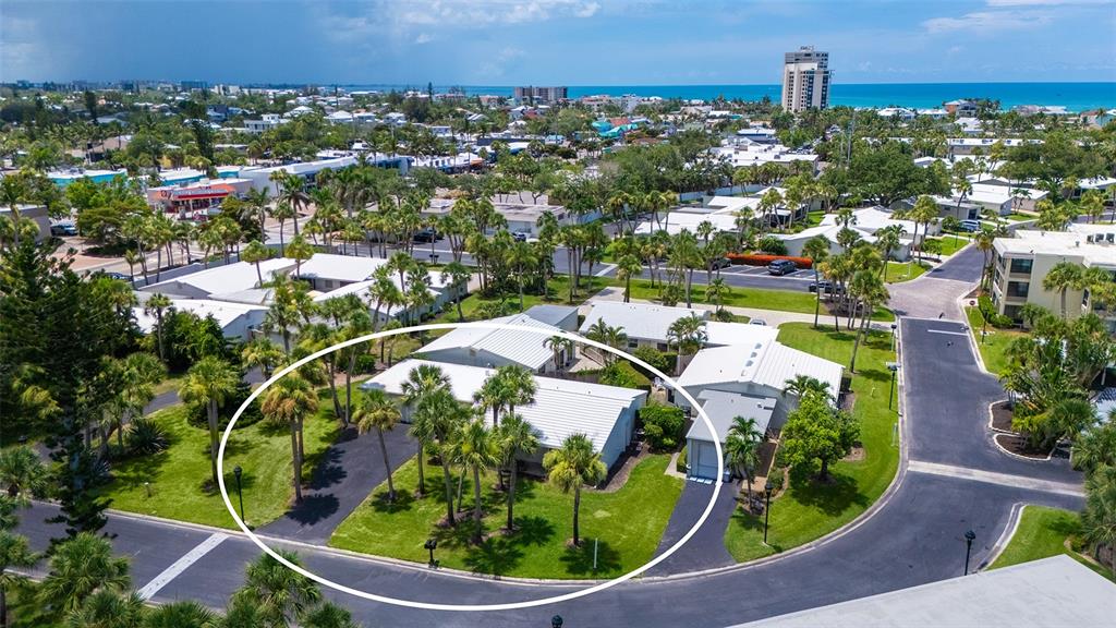 An aerial view shows a single-story house with a white roof surrounded by palm trees — 208 HOURGLASS WAY UNIT V11, SARASOTA, FL