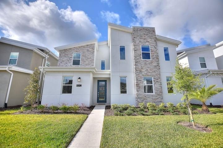 A modern two-story house features white stucco siding, stone accents, and a central front entrance — 4542 NARRATIVE LANE, KISSIMMEE, FL