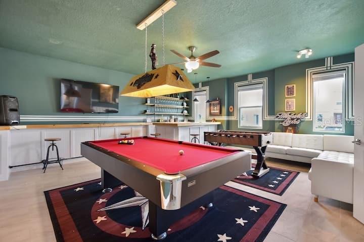 A game room features a pool table, foosball table, bar area, and white sectional sofa — 4542 NARRATIVE LANE, KISSIMMEE, FL