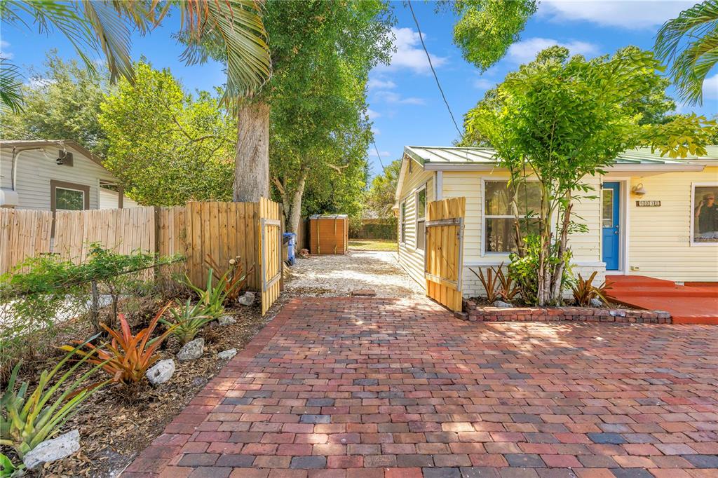 A brick driveway leads to a yellow house with a blue door and wooden fence — 5032 19TH STREET N, ST PETERSBURG, FL