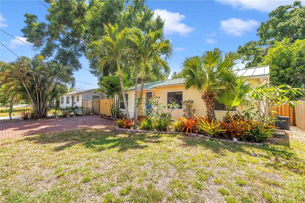 A yellow cottage with a metal roof, palm trees, and a brick driveway — 5032 19TH STREET N, ST PETERSBURG, FL