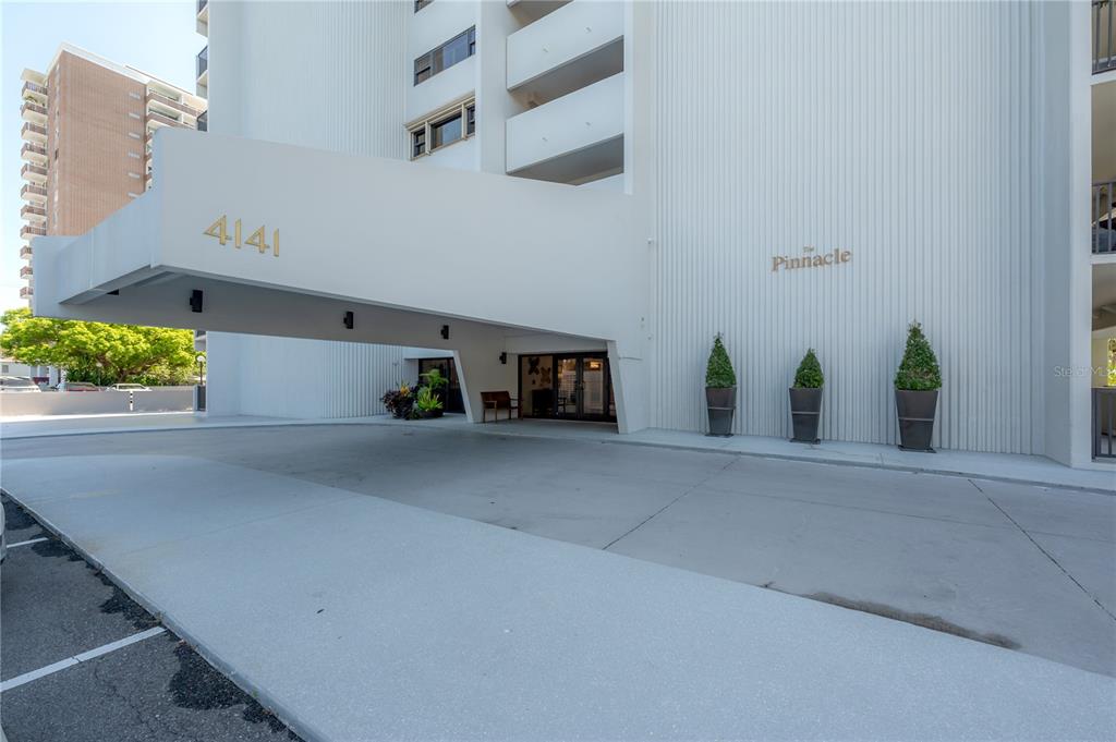 The exterior entrance of a white high-rise building features a large covered porte-cochère — 4141 BAYSHORE BOULEVARD UNIT 1003, TAMPA, FL