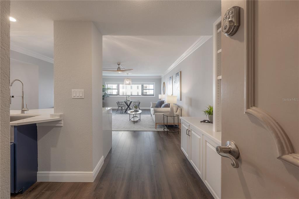 An entryway leads into a living room with wood-look flooring, white cabinetry, and a kitchen — 4141 BAYSHORE BOULEVARD UNIT 1003, TAMPA, FL