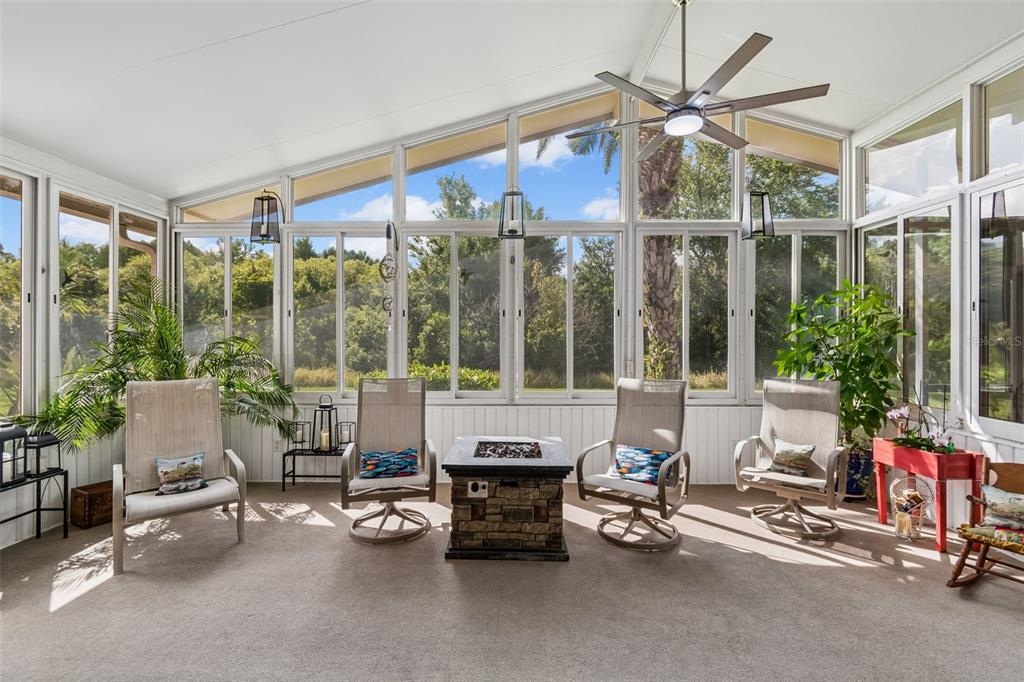 A sunroom features a vaulted ceiling, a ceiling fan, large windows, and four patio chairs — 184 VENTANA DR, POINCIANA, FL