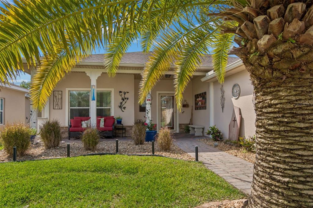A single-story house exterior features a covered front porch, red chairs, and a palm tree — 184 VENTANA DR, POINCIANA, FL