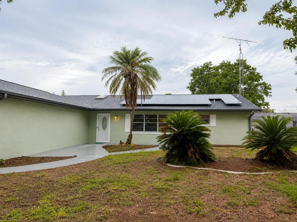 A light green house with a palm tree, solar panels, and a concrete walkway — 4401 MADERIA AVENUE, SEBRING, FL