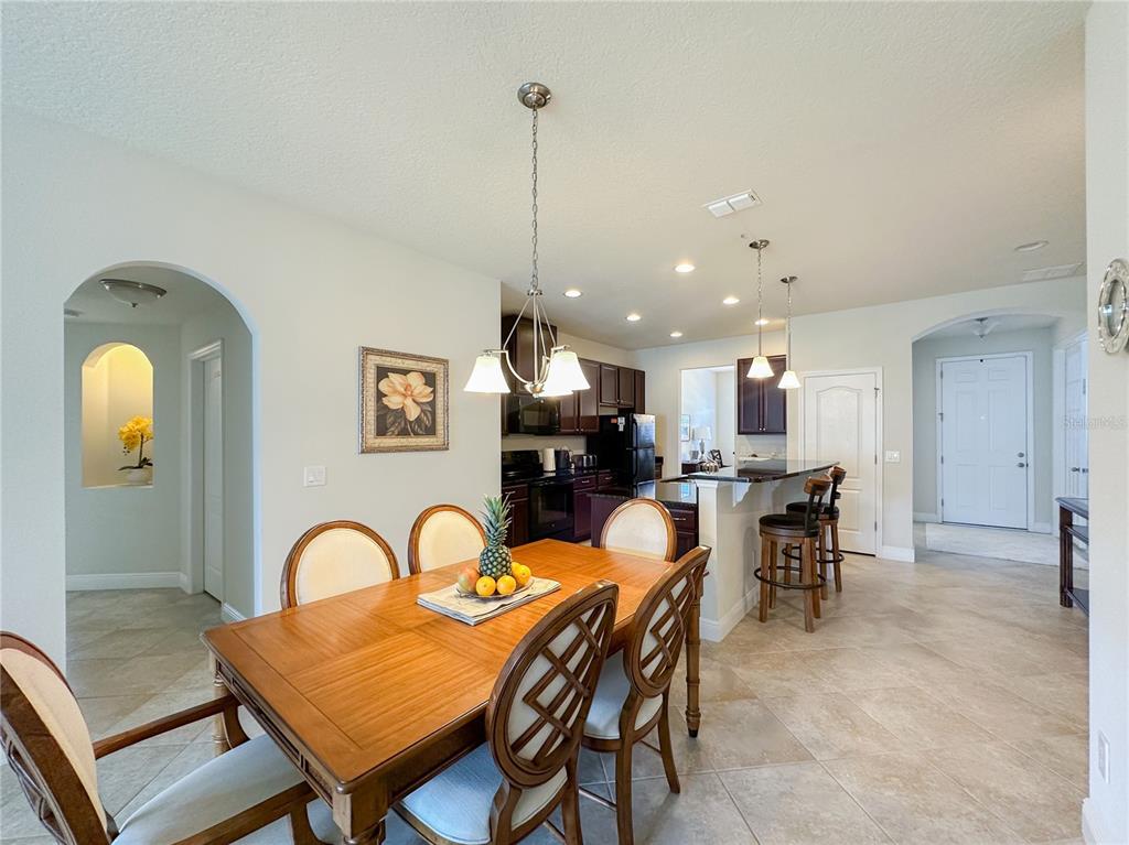 A dining area with a wooden table leads into a kitchen with dark cabinetry — 720 PARKMONT PLACE, WINTER GARDEN, FL