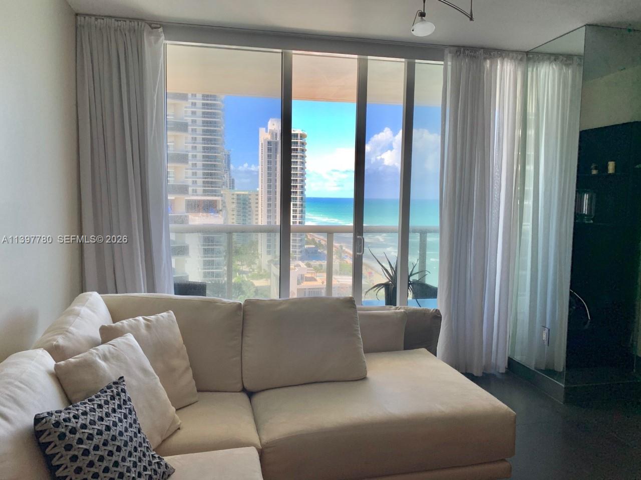 A living room features a beige sectional sofa facing floor-to-ceiling windows with ocean views — 1830 S Ocean Dr # 1610, Hallandale Beach FL 33009, HALLANDALE BEACH, FL