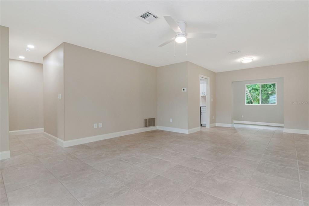 An open-concept living area features light-colored tile flooring, beige walls, and a ceiling fan — 2958 DUNDEE DRIVE, PALM HARBOR, FL