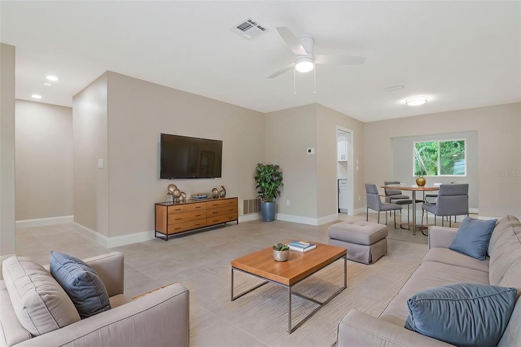 A living room features light tile floors, a wall-mounted television, and a dining area beyond — 2958 DUNDEE DRIVE, PALM HARBOR, FL