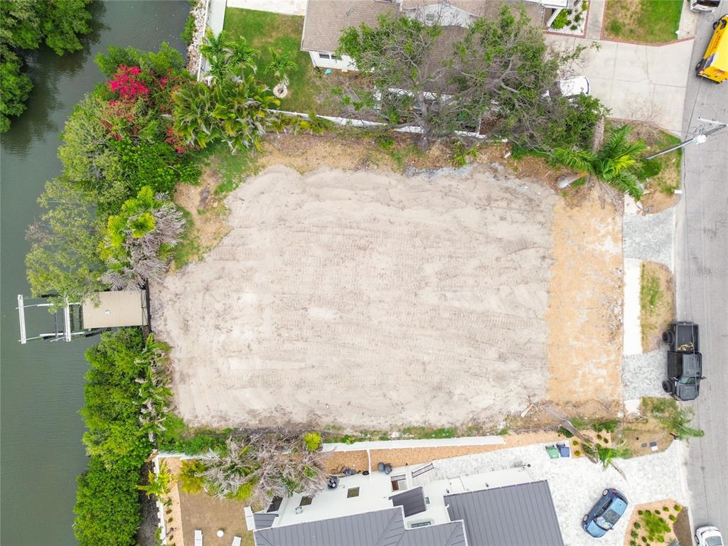 An aerial view shows a cleared, sandy vacant lot situated between two houses and water — 17 W SPANISH MAIN STREET, TAMPA, FL