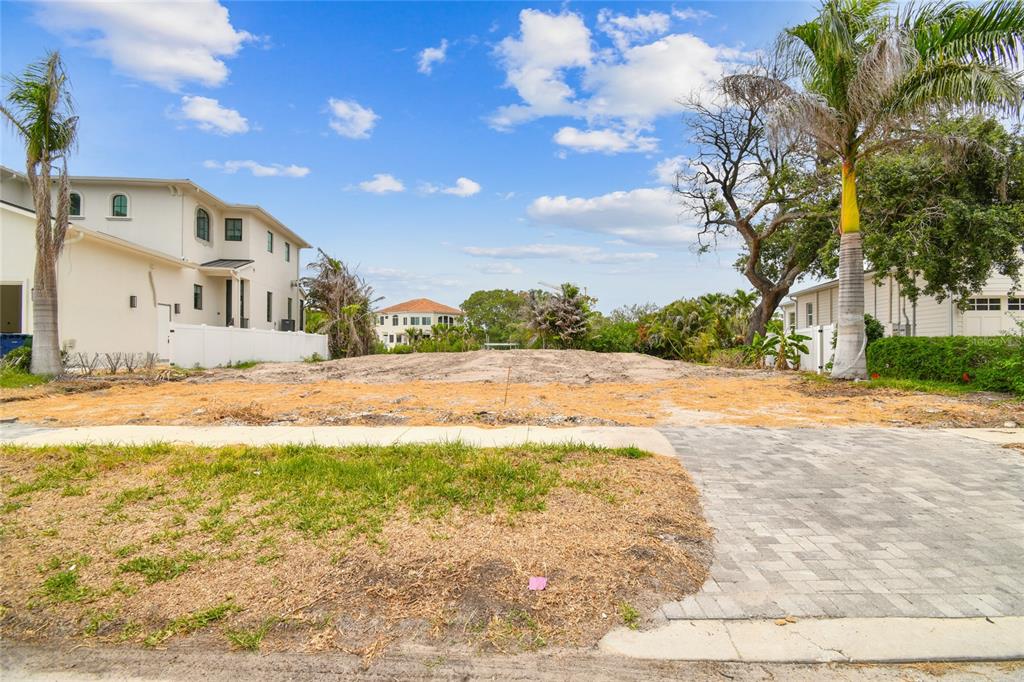 A vacant, sandy residential lot sits between two houses under a blue sky with clouds — 17 W SPANISH MAIN STREET, TAMPA, FL