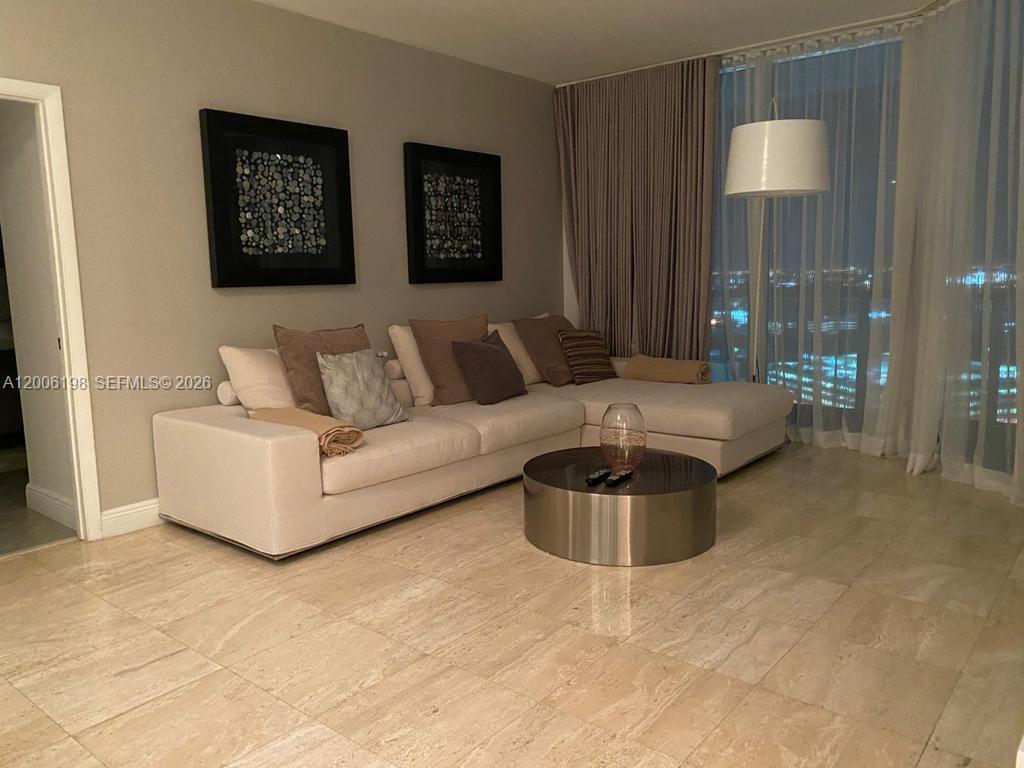 A living room features a large sectional sofa, a round coffee table, and floor-to-ceiling curtains — 1900 N Bayshore Dr # 2314, Miami FL 33132, MIAMI, FL