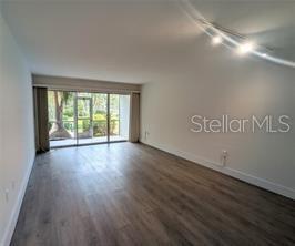 An empty living room with wood-look flooring and sliding glass doors leading to a patio — 2155 WOOD STREET UNIT A7, SARASOTA, FL