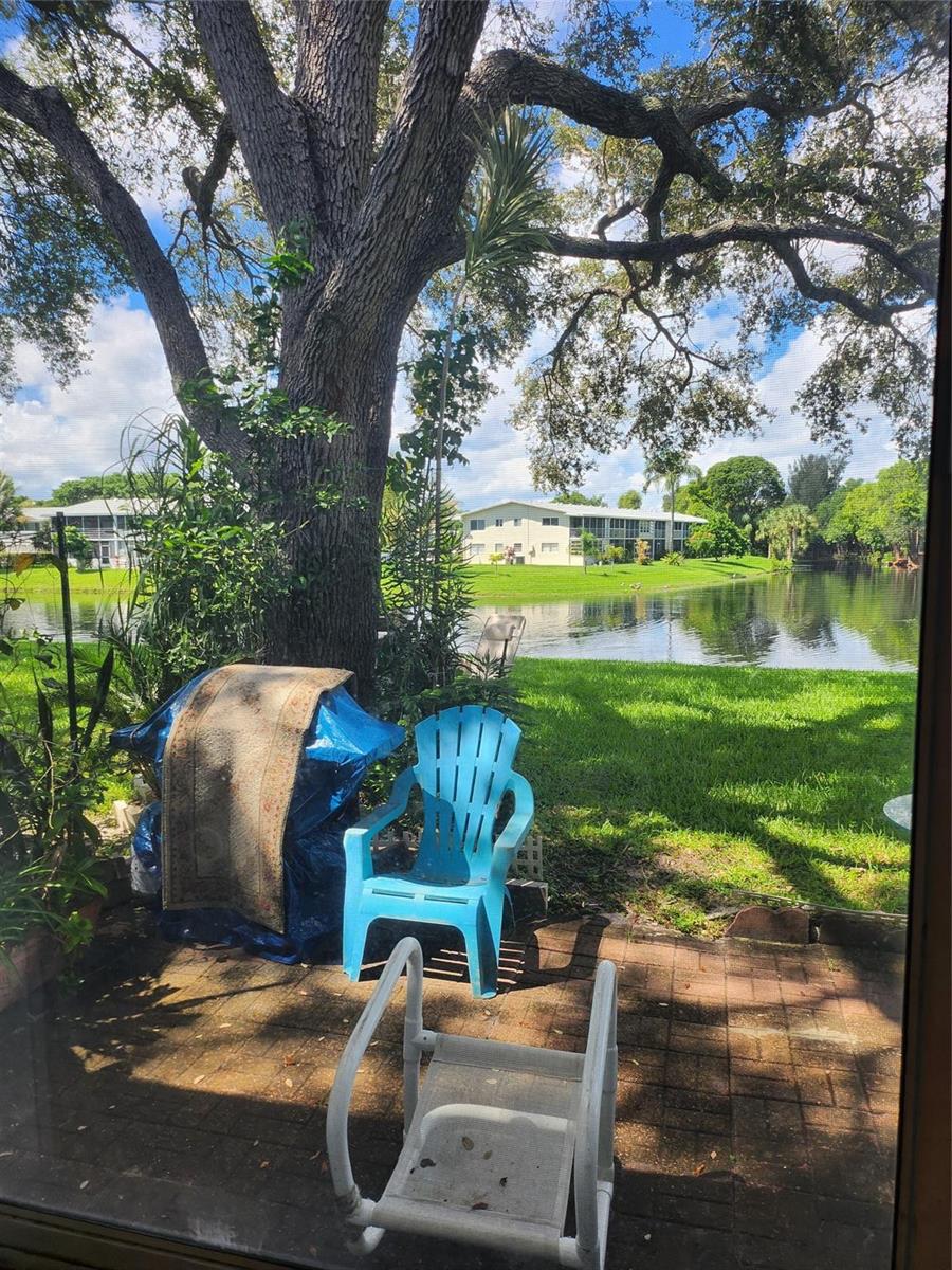 A view from a patio looking out toward a lake, trees, and apartment buildings — 104 Westbury E, Deerfield Beach FL 33442, DEERFIELD BEACH, FL