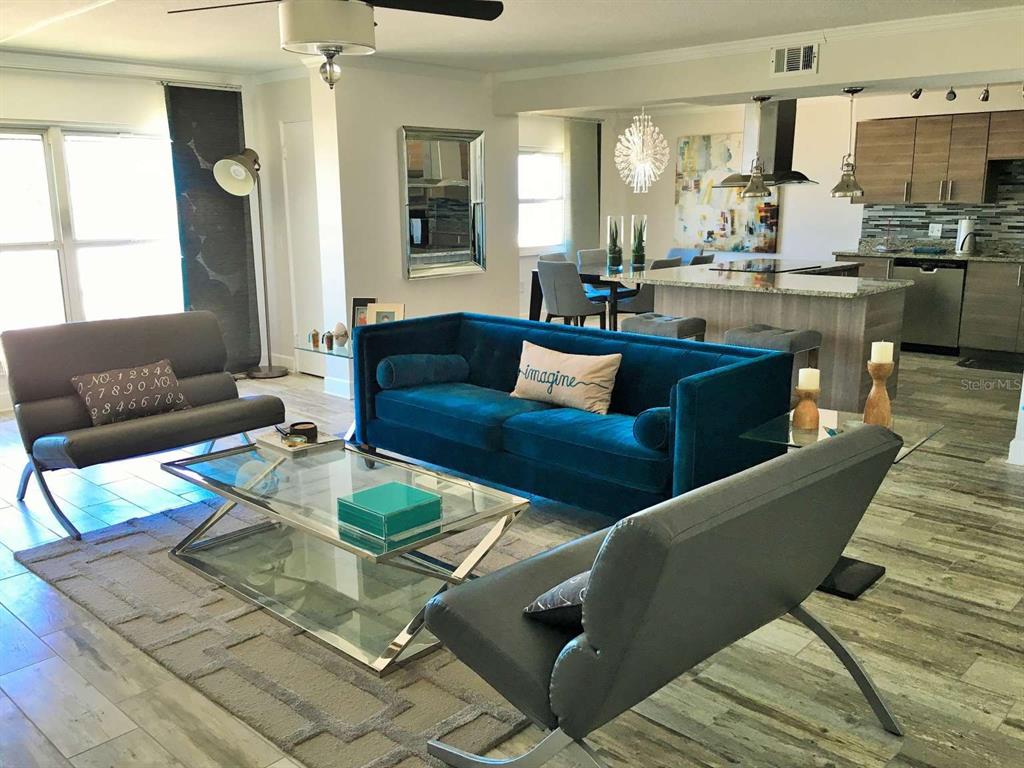 A living room features a blue velvet sofa, two gray chairs, and a glass coffee table — 5000 GULF BOULEVARD UNIT 303, ST PETERSBURG, FL