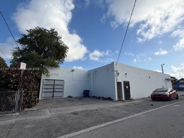 A white, single-story commercial building with a metal gate and a parked red car — 102 NW 22nd Ave, Miami FL 33125, MIAMI, FL