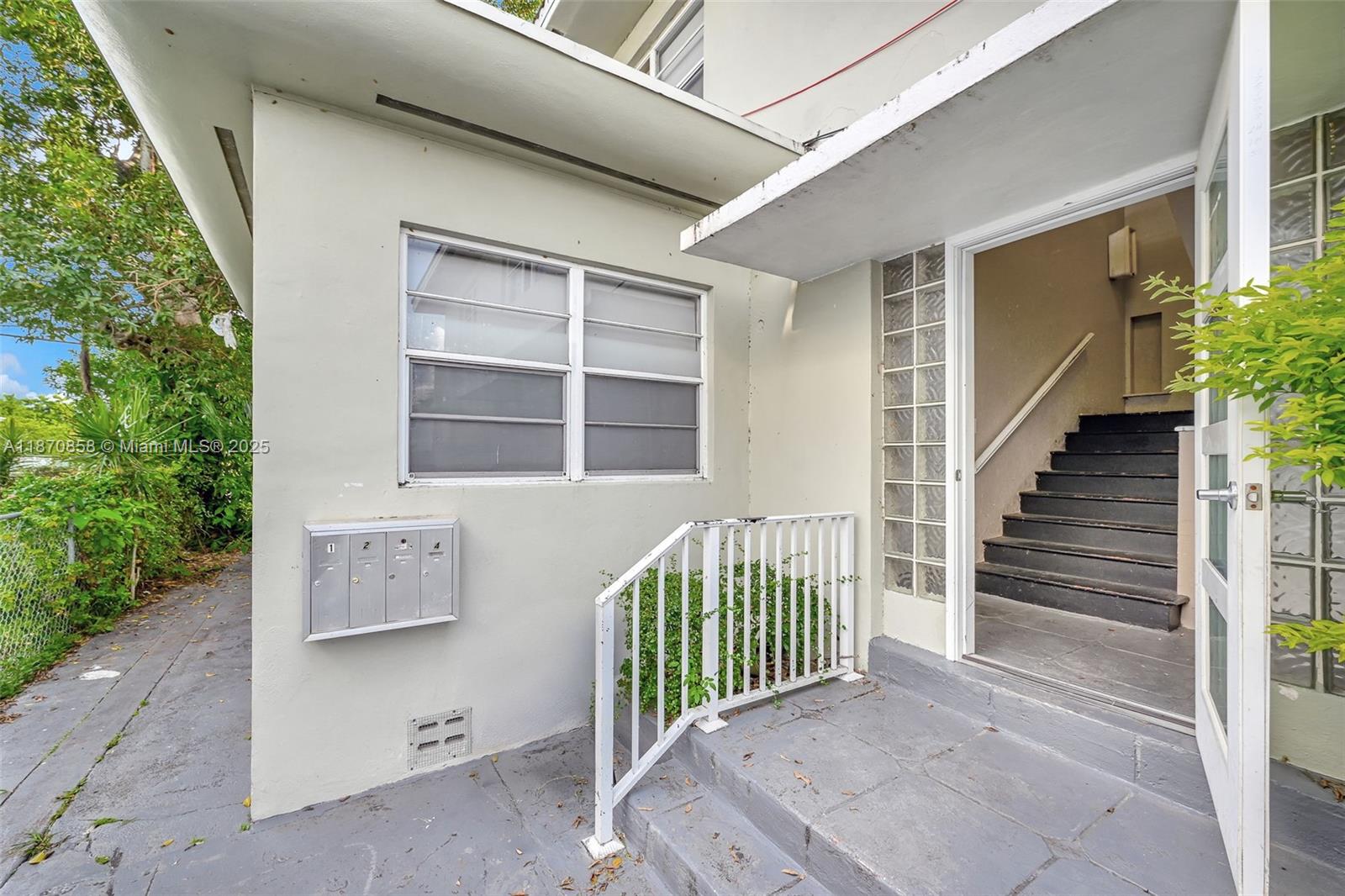 The exterior of a building features a staircase entrance, a window, and metal mailboxes — 1784 Marseille Dr, Miami Beach FL 33141, MIAMI BEACH, FL