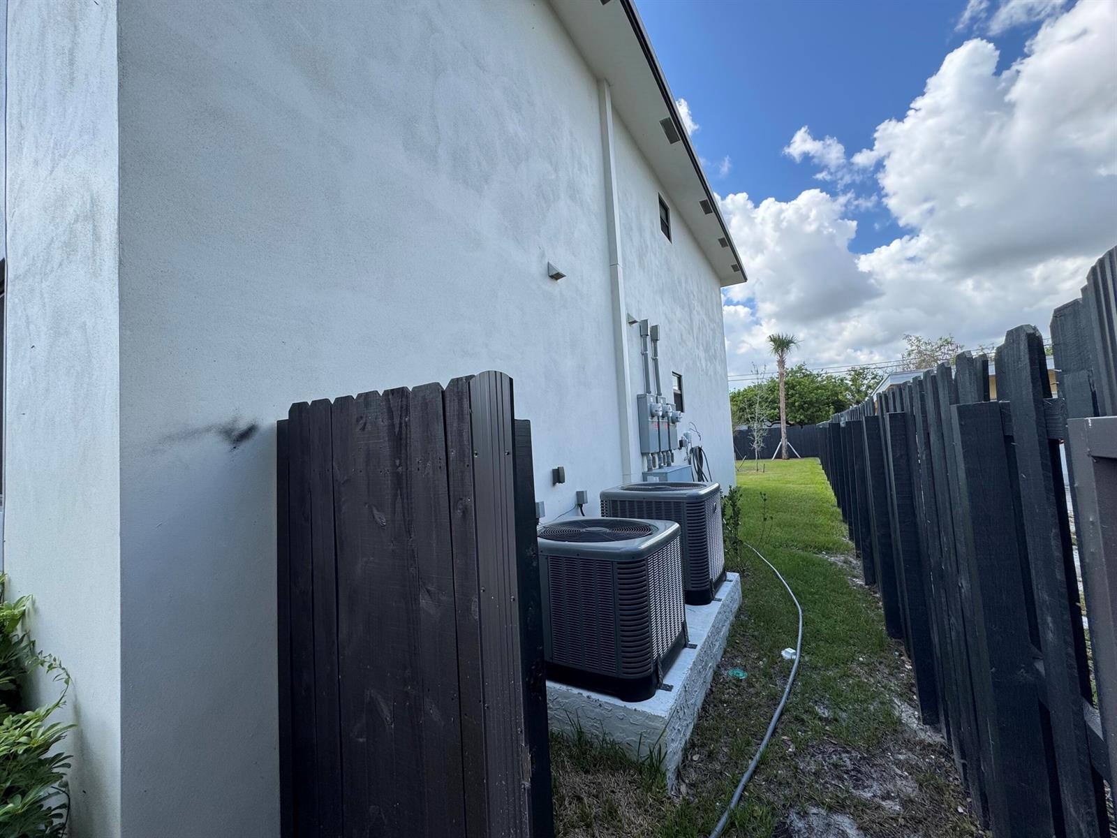 The exterior side of a white house features two HVAC units and a black fence — 400 NE 30th Street # 2, Pompano Beach FL 33064, POMPANO BEACH, FL