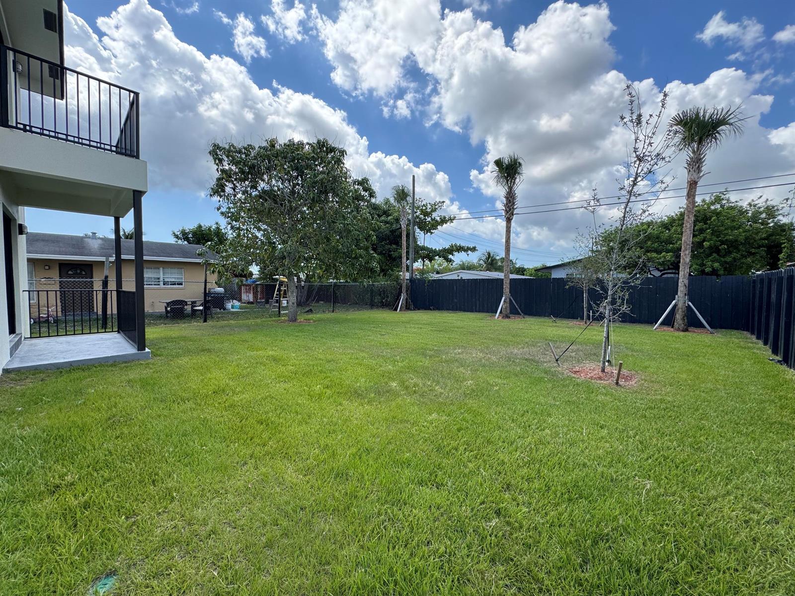 A grassy backyard features a patio, a large tree, and two palm trees by a fence — 400 NE 30th Street # 2, Pompano Beach FL 33064, POMPANO BEACH, FL