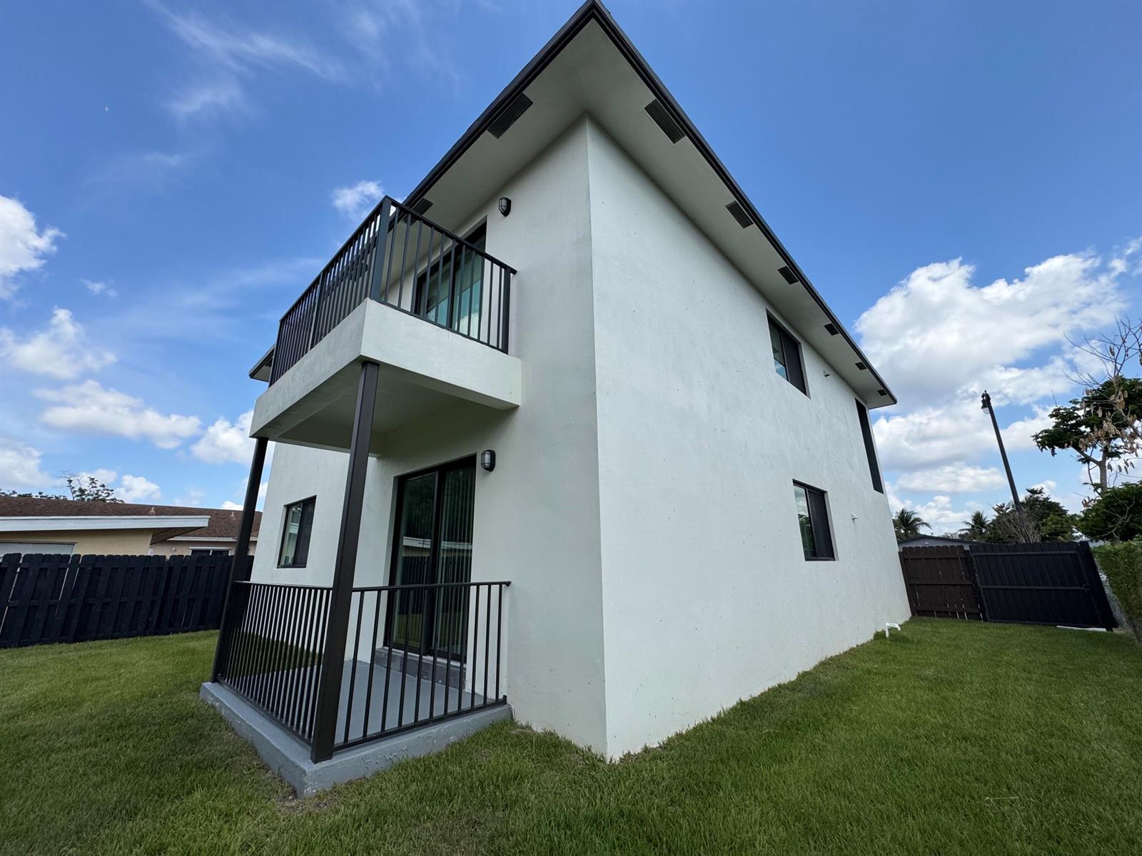 A two-story white stucco house features a balcony and a ground-level patio with black railings — 400 NE 30th Street # 2, Pompano Beach FL 33064, POMPANO BEACH, FL