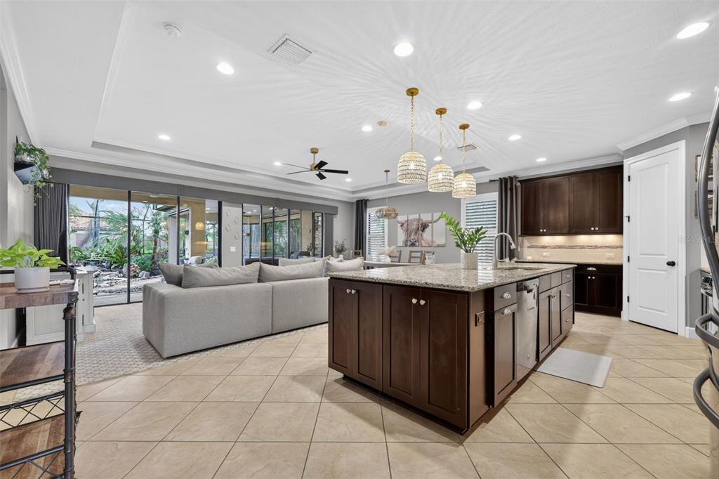 A kitchen with a large dark wood island, granite countertops, and an adjacent living area — 13202 PRIMA DRIVE, BRADENTON, FL