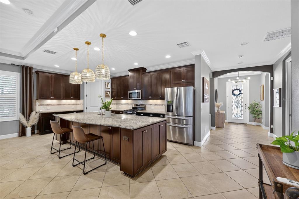 A kitchen features dark wood cabinets, granite countertops, a large island, and tile flooring — 13202 PRIMA DRIVE, BRADENTON, FL